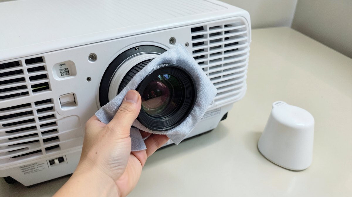 Nettoyer la lentille d'un vidéoprojecteur avec un chiffon microfibre et une poire soufflante